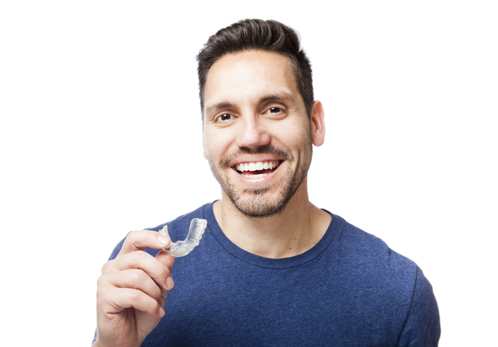 Happy man holding a clear aligner